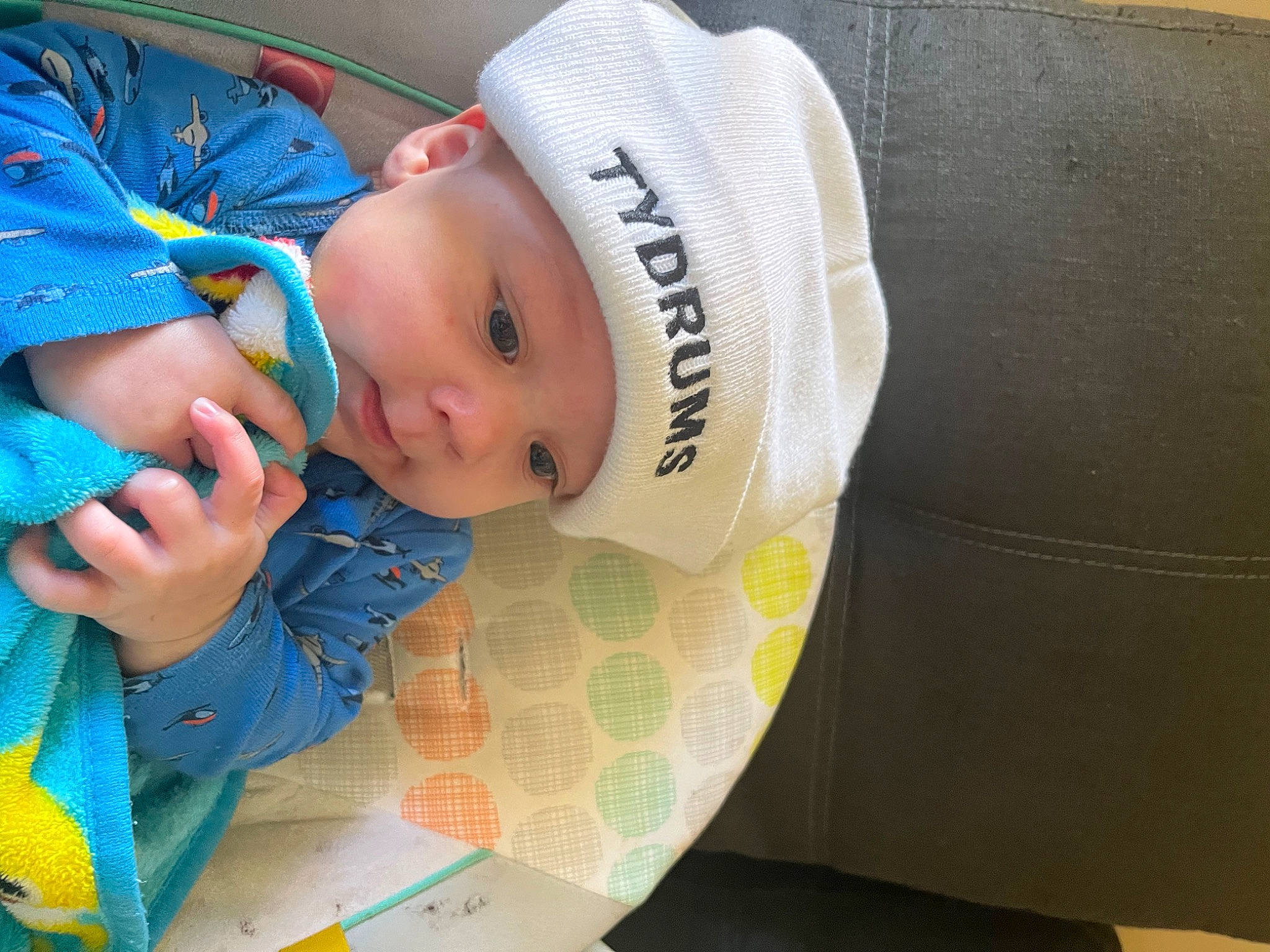 Cooper is registered to the contest to win money with this photo: baby, baby_products, baby_safety, baby_toddler_clothing, beanie, cap, cheek, child, comfort, fashion_accessory, happy, headwear, knit_cap, linens, nail, pattern, person, room, sitting, sleeve
