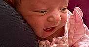 Evangeline joined the competition — help win amazing prizes! baby, newborn, infant, pink_clothing, person, face, head, expression, closeup, indoors, pillow, fabric, human, skin, curly_hair, soft_light, candid, holding, comfort, cute