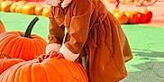 Saanvi is registered to the contest to win money with this photo: child, clothing, coat, face, female, food, footwear, girl, happy, head, person, photography, plant, portrait, produce, pumpkin, sitting, smile, squash, vegetable
