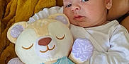 Matéo a rejoint le concours — aidez-le/la à gagner de superbes lots ! baby, infant, plush_toy, stuffed_animal, blanket, couch, white_clothing, soft_toy, indoor, child, person, cute, cozy, resting, face, head, expression, holding, comfort, home