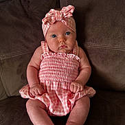 Adeline joined the competition — help win amazing prizes! baby, infant, child, pink_clothing, headband, blue_eyes, sitting, couch, brown_furniture, indoors, cute, portrait, chubby_cheeks, fist, gazing, soft_lighting, plaid_pattern, young, person, cozy