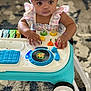 baby, infant, child, toy, walker, headband, striped_clothing, hands, carpet, indoor, play, colorful, music_toy, floor, person, cute, closeup, focus, entertainment, young