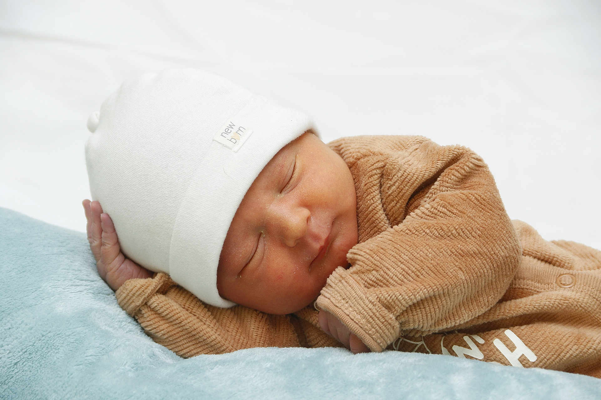 Sasha a rejoint le concours — aidez-le/la à gagner de superbes lots ! newborn, baby, sleeping, hat, white_hat, brown_outfit, soft_texture, blanket, blue_blanket, infant, peaceful, cute, portrait, child, resting, closeup, indoors, cozy, human, headwear