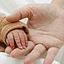 baby_hand, adult_hand, skin, gesture, touch, human, fingers, baby_clothing, protection, bond, closeup, interaction, parent_child, comfort, warmth, family, love, care, skin_texture, hand_size_comparison