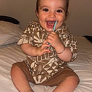 Sinaï participe au concours pour gagner de l'argent avec cette photo : baby, child, smiling, happy, sitting, bed, clothing, shorts, shirt, patterned, indoors, chewing, straw, bracelet, feet, toes, portrait, cute, person, home