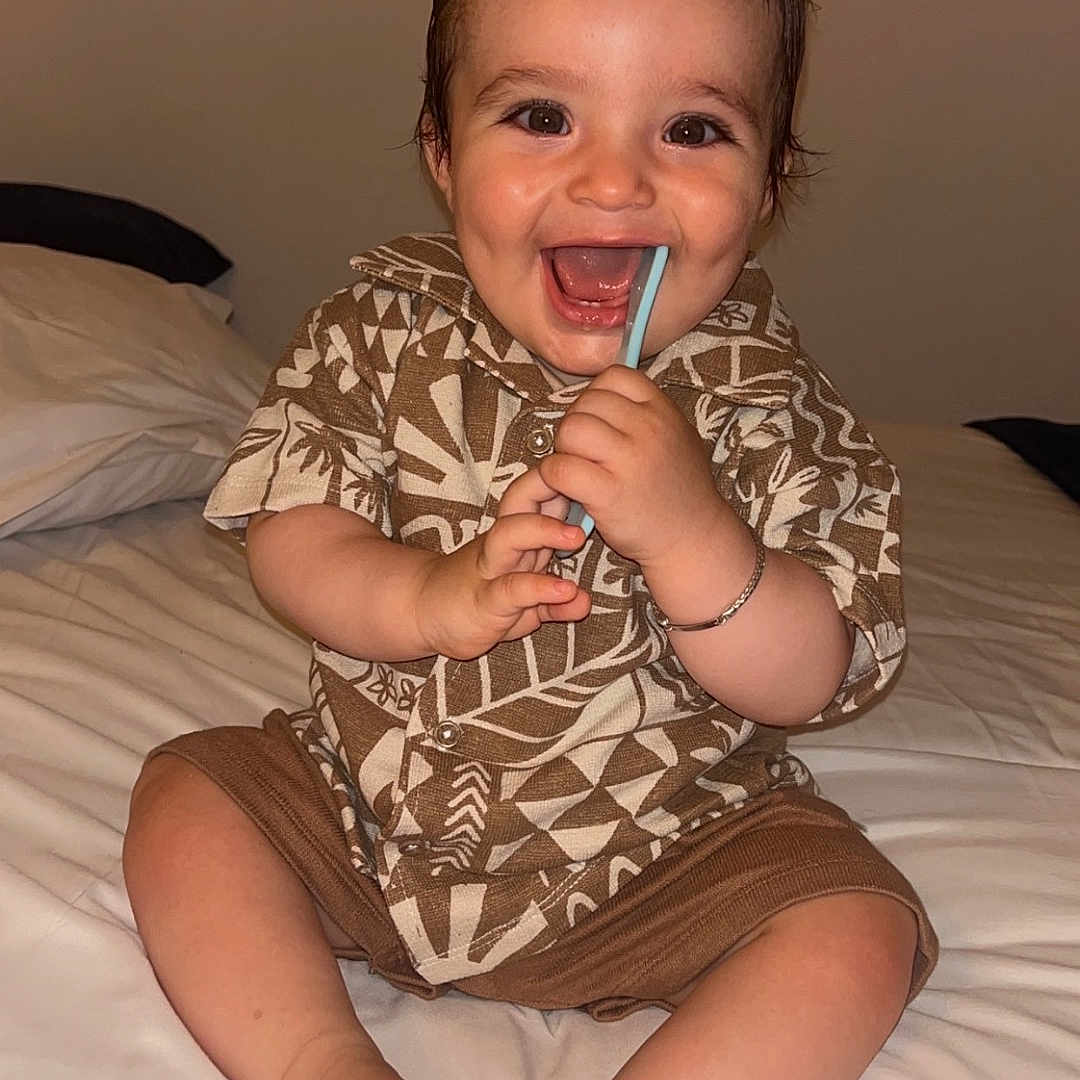 Sinaï participe au concours pour gagner de l'argent avec cette photo : baby, bed, bracelet, chewing, child, clothing, cute, feet, happy, home, indoors, patterned, person, portrait, shirt, shorts, sitting, smiling, straw, toes