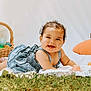 Alyza is registered to the contest to win money with this photo: baby, smiling, curly_hair, blue_dress, grass, blanket, easter_eggs, basket, outdoor, happy, child, portrait, cute, infant, lying_down, nature, playful, sunlight, celebration, easter