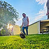 Teddy joined the competition — help win amazing prizes! man, dog, grass, tree, shed, sunlight, outdoor, sky, clouds, building, bench, casual_clothing, running, pet, nature, daytime, greenery, sunflare, yard, playful