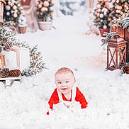 Zak is registered to the contest to win money with this photo: baby, child, snow, winter, holiday, christmas, lantern, pine_cone, greenery, red_clothing, white_fluff, festive, decorations, candle, smiling, cute, indoors, portrait, seasonal, happy