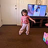 Emerson joined the competition — help win amazing prizes! toddler, child, headphones, pink_shirt, sweatpants, shoes, carpet, living_room, television, bird_video, wooden_furniture, door, wall, playful_pose, indoor, person, cute, expression, casual_clothing, home