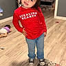 child, red_shirt, jeans, sneakers, indoor, floor, rug, door, cabinet, playful, smile, pose, hair, face, person, wooden_floor, children, casual_clothing, home, background