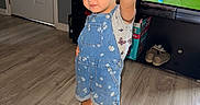 Emerson is registered to the contest to win money with this photo: child, girl, denim_overalls, pink_sandals, indoor, living_room, wooden_floor, television, sports, pose, hand_raised, cute, smiling, short_hair, casual_clothing, home, playful, flooring, door, furniture