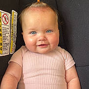 Rivlynn is registered to the contest to win money with this photo: baby, child, car_seat, pink_clothing, blue_eyes, smiling, topknot, blanket, indoor, cute, infant, person, seat, portrait, happy, skin, head, hand, furniture, wood_floor