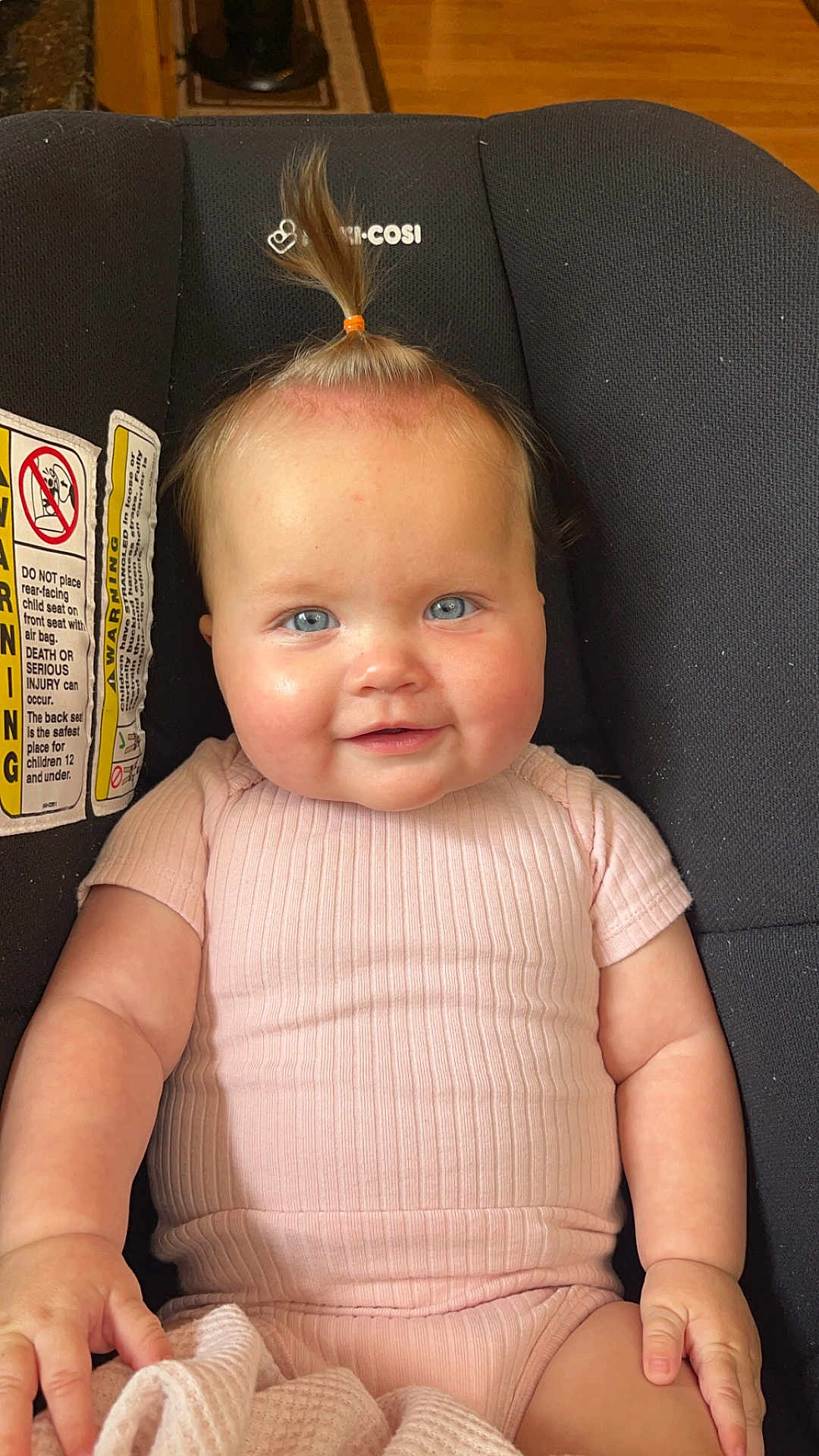Rivlynn is registered to the contest to win money with this photo: baby, child, car_seat, pink_clothing, blue_eyes, smiling, topknot, blanket, indoor, cute, infant, person, seat, portrait, happy, skin, head, hand, furniture, wood_floor