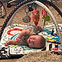Milo is registered to the contest to win money with this photo: baby, play_mat, toy, carpet, rug, infant, floor, smiling, lying_down, colorful, soft_toy, indoor, child, person, home, furniture, chair, cable, patterned, cozy
