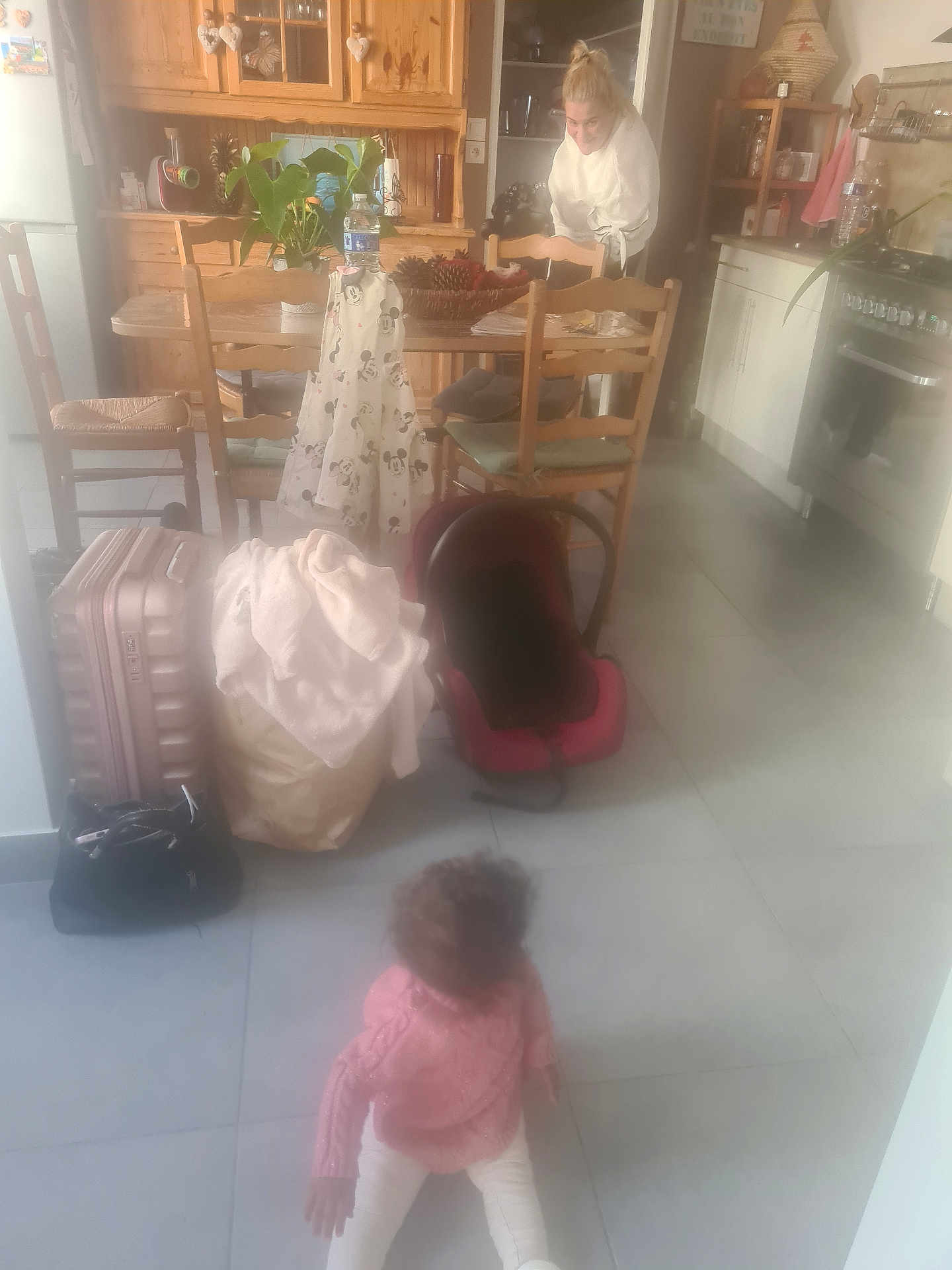 Keylah participe au concours pour gagner de l'argent avec cette photo : child, baby, kitchen, person, furniture, chair, table, suitcase, bag, plant, car_seat, wooden_cabinet, adult, floor, clothing, pink_sweater, white_pants, indoor, tile_floor, home