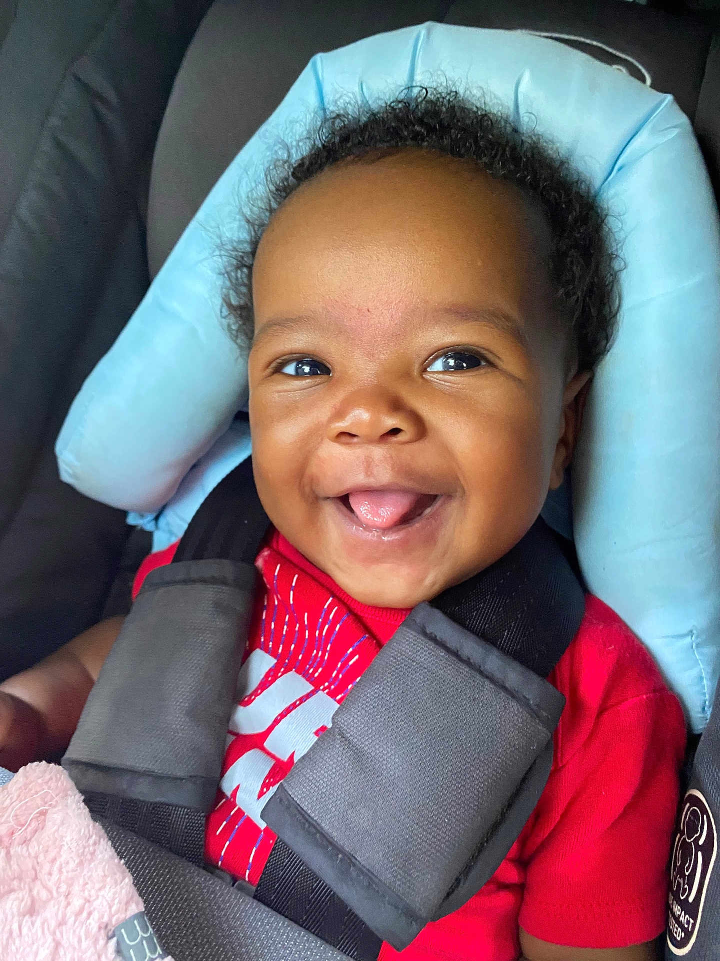 Nylah joined the competition — help win amazing prizes! baby, child, car_seat, smile, tongue_out, red_shirt, seatbelt, black_hair, happy, cute, infant, portrait, closeup, indoors, baby_clothing, car_interior, seat_padding, secure, young_child, person