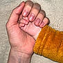 adult_hand, baby_hand, holding, close_up, skin, fingers, nails, orange_sleeve, fabric, texture, blanket, soft, tenderness, connection, human, touch, care, comfort, warmth, skin_tone