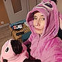 person, dog, plush_outfit, matching_clothes, hoodie, pink, indoor, selfie, pet, costume, canine, face, cute, cozy, home, furniture, table, door, expression, animal