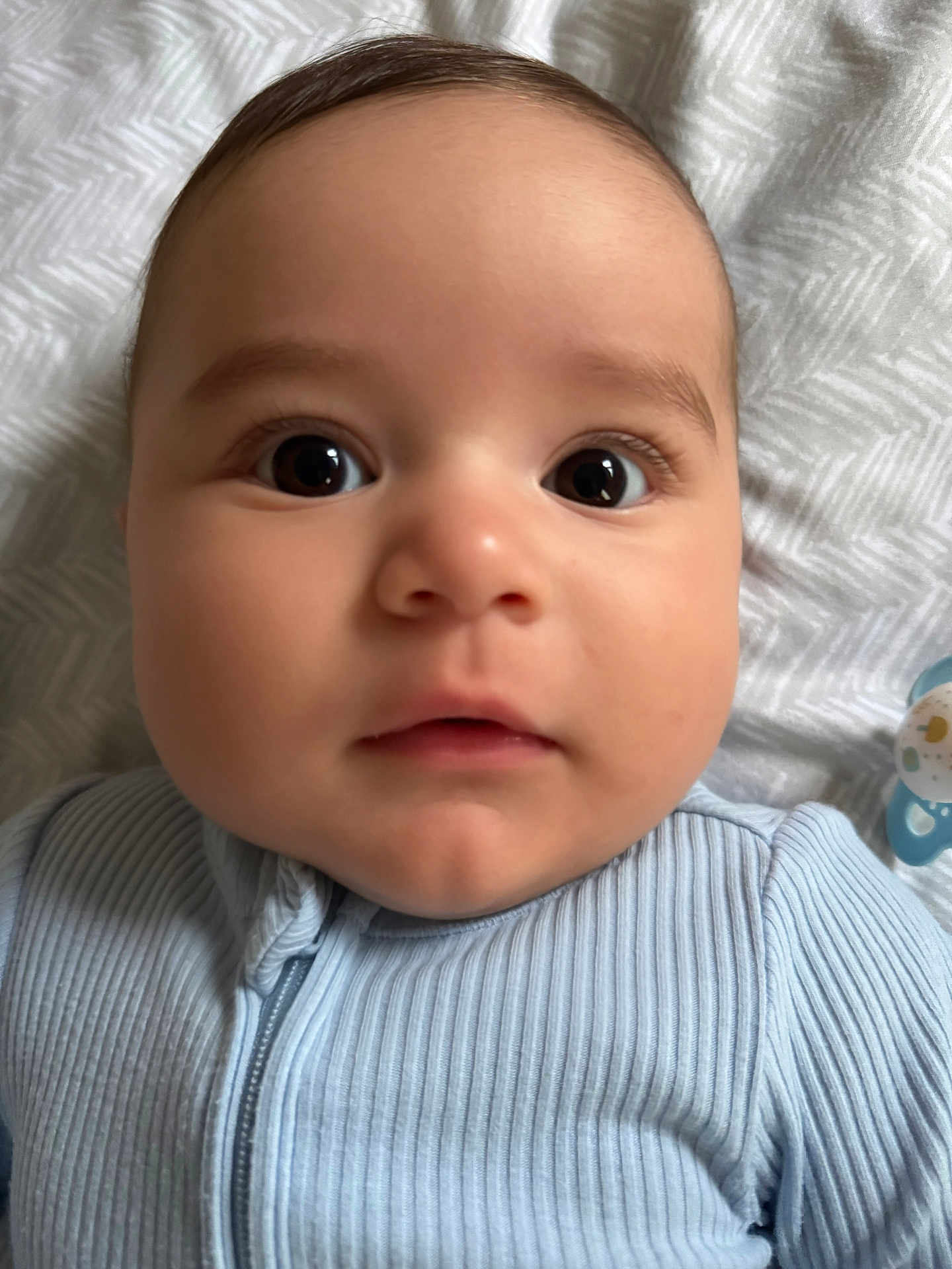Zen is registered to the contest to win money with this photo: baby, close_up, face, infant, child, eyes, blanket, pacifier, clothing, ribbed_fabric, cute, portrait, lying_down, soft_light, indoor, skin, mouth, nose, head, young