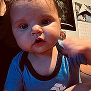 Murdok joined the competition — help win amazing prizes! baby, child, face, person, indoor, clothing, blue_shirt, hair, skin, hand, arm, lap, fabric, gnome_pattern, poster, wall, calendar, curious, closeup, seated