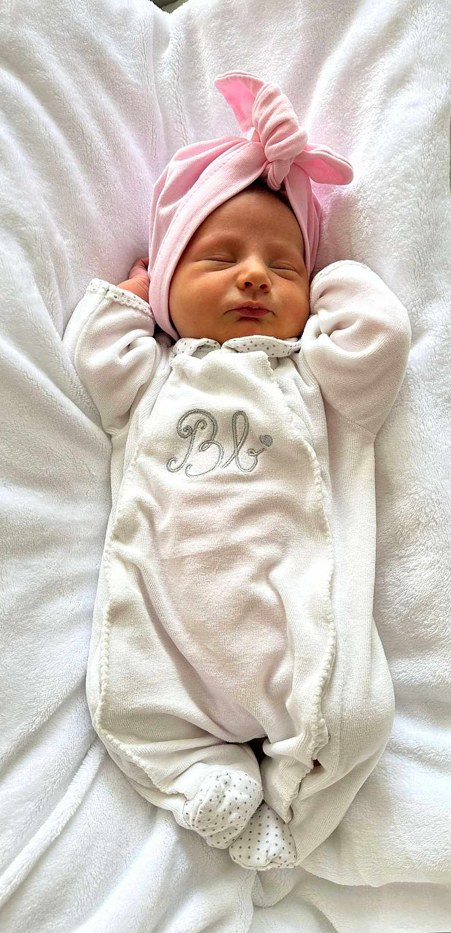 Agathe a rejoint le concours — aidez-le/la à gagner de superbes lots ! baby, newborn, infant, sleeping, white_blanket, pink_hat, cozy, cute, soft, clothing, footed_pajamas, portrait, peaceful, resting, indoors, child, person, headwear, sleep, small