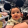 baby, child, mouse_ears, headband, smiling, indoor, store, clothing, shelf, person, cute, face, holding, shopping, bright_lights, curious, toddler, apparel, human, portrait