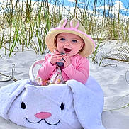 Montana joined the competition — help win amazing prizes! baby, beach, clothing, coast, face, grass, hat, head, nature, outdoors, person, photography, plant, portrait, sea, shoreline, sitting, soil, sunhat, water