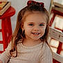 Laney is registered to the contest to win money with this photo: beige_dress, chair, child, cute, earrings, face, girl, happy, indoor, light, long_hair, person, portrait, red_bow, red_stool, sitting, smile, warm, wooden, young