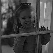 Laney is registered to the contest to win money with this photo: black_and_white, child, curtain, cute, dress, face, girl, glass, hands, happy, indoors, light, long_hair, portrait, reflection, shadow, smile, texture, window, young