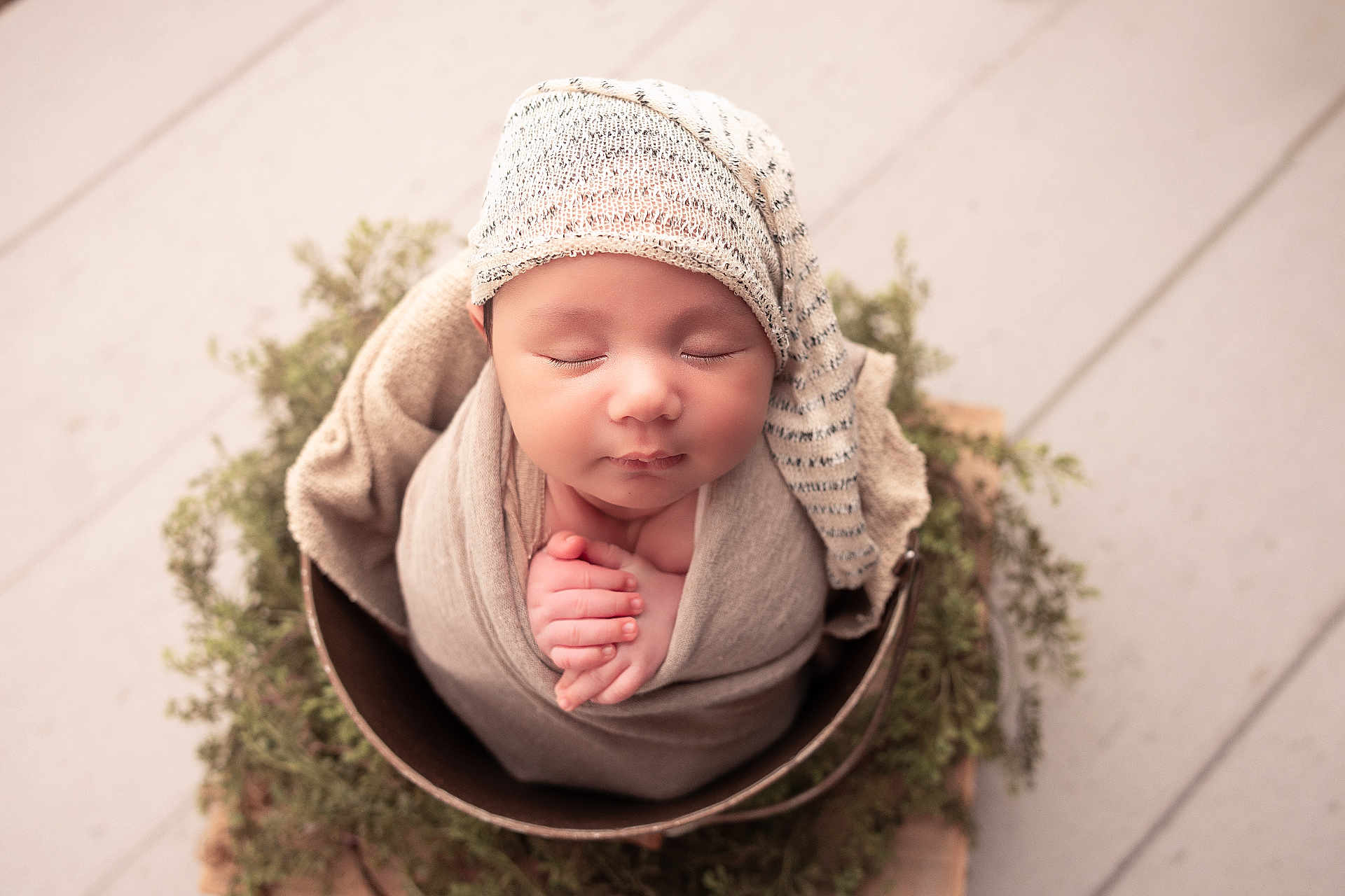 Matthew is registered to the contest to win money with this photo: newborn, baby, sleeping, wrapped, hat, bucket, greenery, soft, cozy, peaceful, infant, cute, portrait, indoors, hands, headwear, blanket, wooden_floor, nature, resting