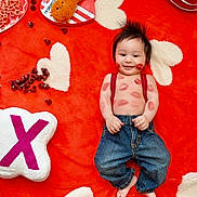 Matthew is registered to the contest to win money with this photo: baby, infant, smiling, kiss_marks, denim_jeans, red_suspender, heart_pattern, red_blanket, plush_cushion, candy, valentines_theme, cute, child, happy, indoor, playful, face, small_hands, barefoot, cozy