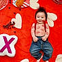 baby, infant, smiling, kiss_marks, denim_jeans, red_suspender, heart_pattern, red_blanket, plush_cushion, candy, valentines_theme, cute, child, happy, indoor, playful, face, small_hands, barefoot, cozy