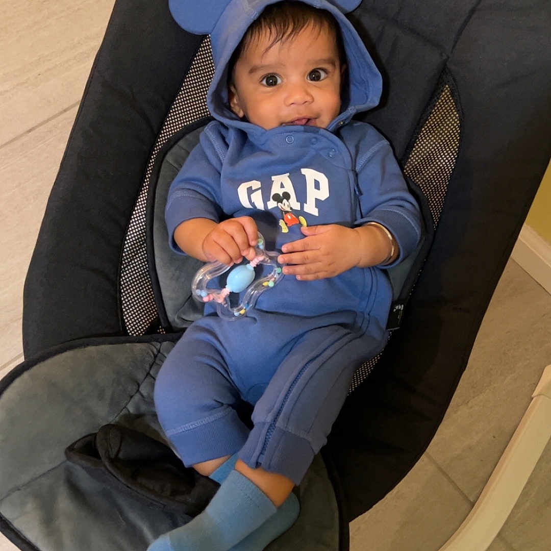 Gurnawab is registered to the contest to win money with this photo: baby, blue_clothing, hoodie, mouse_ears, toy, baby_rocker, indoor, floor, curious, smile, child, infant, socks, casual_wear, person, cute, seated, comfortable, bright_eyes, young_child