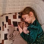 child, baby, sleeping, crib, embracing, tender, cozy, bedding, geometric_pattern, blanket, bedroom, indoor, family, love, comfort, clothing, girl, infant, portrait, rest