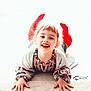 child, smiling, red_socks, patterned_sweater, happy, face, hands, lying_down, carpet, indoor, cute, portrait, young, playful, light_background, bright, joyful, person, feet, casual_clothing