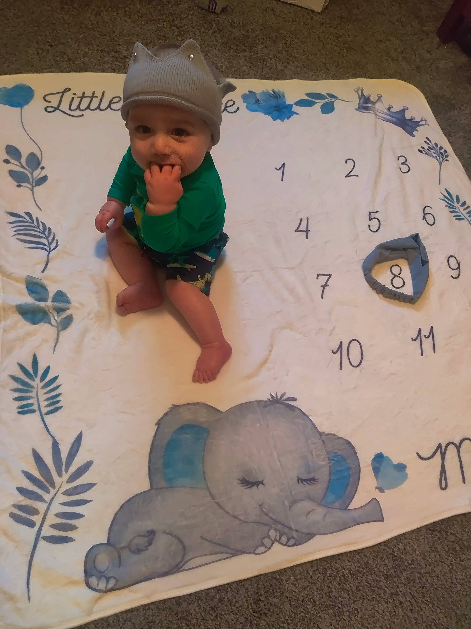 Izac is registered to the contest to win money with this photo: baby, baby_toddler_clothing, baby_toys, bedding, cap, child, comfort, flooring, font, happy, headwear, illustration, linens, mammal, pattern, person, room, smile, t_shirt, textile