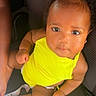 baby, child, yellow_clothing, yellow_bow, car_seat, infant, cute, portrait, skin, eyes, hair, sitting, person, one_person, indoors, seatbelt, foot, hand, looking_up, adorable