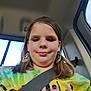 Gracie is registered to the contest to win money with this photo: child, car, seatbelt, selfie, tie_dye_shirt, earrings, pink_lipstick, window, daylight, casual, portrait, young, person, smile, hair, face, clothing, interior, seat, travel