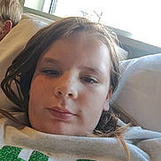 Gracie is registered to the contest to win money with this photo: child, selfie, face, window, pillow, shirt, glitter, green, red, indoor, casual, portrait, young, relaxed, hair, light, bedroom, person, clothing, resting