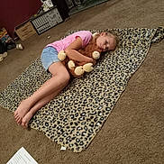 Madalyn Penn joined the competition — help win amazing prizes! child, girl, stuffed_animal, blanket, leopard_print, carpet, indoor, casual_clothing, pink_shirt, denim_shorts, barefoot, relaxing, toy, floor, home, cozy, lying_down, paper, electronics, shelf