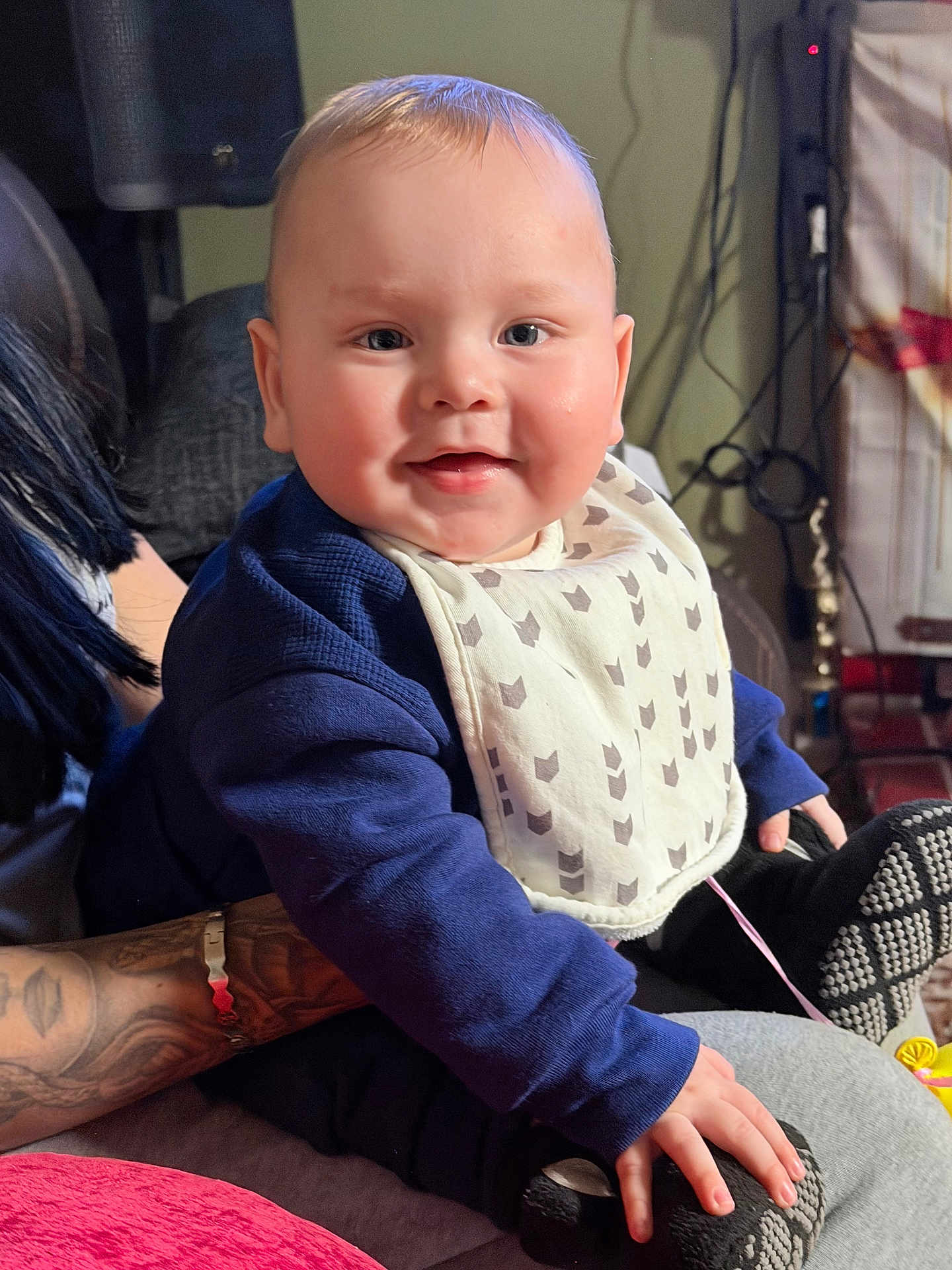 Lukas is registered to the contest to win money with this photo: baby, infant, smile, bib, chubby_cheeks, hand, arm, tattoo, indoors, couch, clothing, portrait, person, toy, footwear, blanket, home_interior, happy, face, eyes