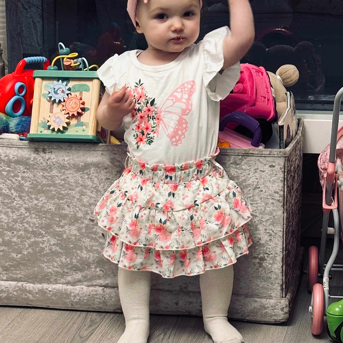 Iylah-Grace joined the competition — help win amazing prizes! bow, child, cute, expression, floor, floral, girl, headband, indoors, person, playroom, pose, skirt, socks, standing, storage_bin, toddler, toys, white_shirt, wooden_floor