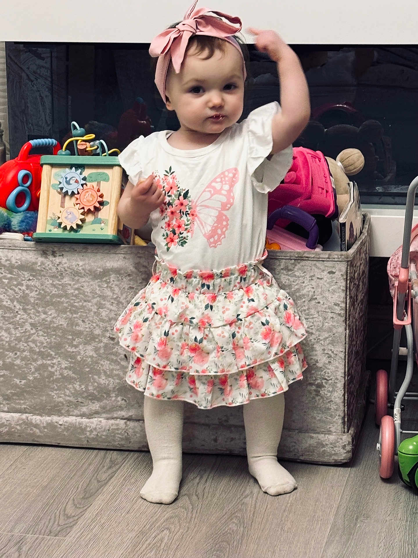 Iylah-Grace joined the competition — help win amazing prizes! toddler, child, girl, headband, bow, skirt, floral, white_shirt, toys, storage_bin, floor, playroom, standing, pose, cute, indoors, socks, wooden_floor, expression, person