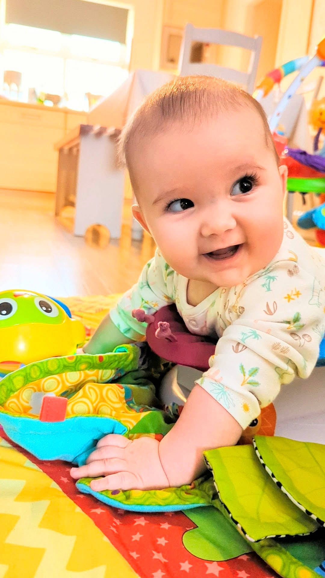 Georgie is registered to the contest to win money with this photo: baby, baby_playing_with_toys, baby_toddler_clothing, cheek, eye, facial_expression, floor, flooring, fun, green, happy, human_body, leisure, orange, person, skin, sleeve, smile, standing, toddler