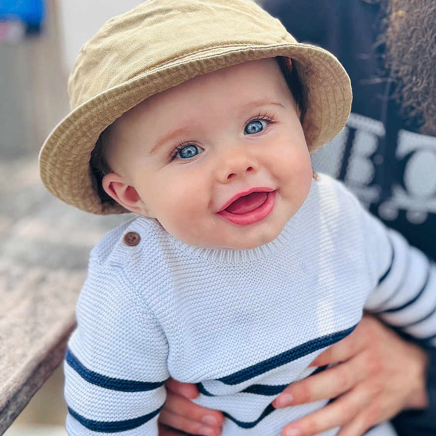 Grayson joined the competition — help win amazing prizes! adult, baby, beard, bench, blue_eyes, casual, child, cute, face, glasses, hand, happy, hat, holding, knitwear, outdoor, person, portrait, smiling, striped_clothing