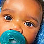baby, pacifier, close_up, face, eyes, curly_hair, skin, blanket, infant, child, cute, portrait, resting, comfort, teal, blue, sleepwear, nose, mouth, expression
