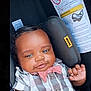 baby, car_seat, infant, bow_tie, shirt, child, smile, hand, clothing, seat, warning_label, cute, portrait, young_child, indoor, face, human, seatbelt, safety, expression