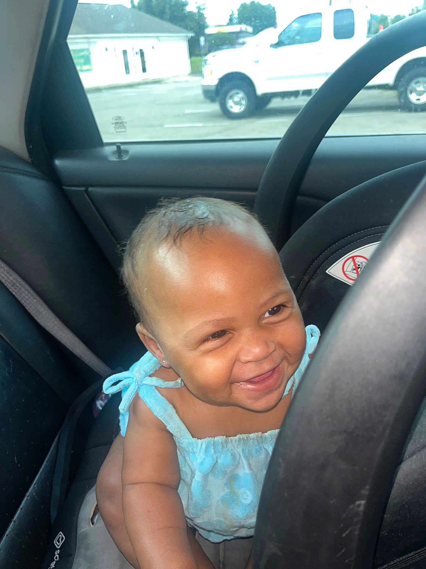 Elani joined the competition — help win amazing prizes! baby, child, car, car_seat, steering_wheel, blue_clothing, smiling, happy, indoors, window, vehicle, seatbelt, face, cute, young_child, transportation, daylight, skin, person, expression