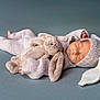 newborn, baby, sleeping, knitted_outfit, bunny_ears, plush_toy, soft_texture, pastel_colors, cute, infant, peaceful, cozy, handmade_clothing, portrait, lying_down, child, adorable, resting, warm, soft_fabric